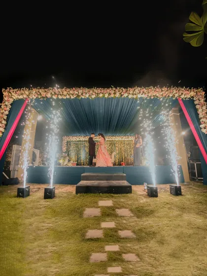 A wide-angle view of the stage where Alankrit and Parul exchange rings, with fireworks adding to the spectacle. This shot highlights the grand scale of the event decor.