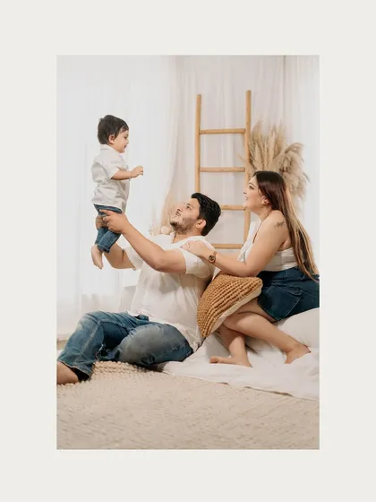 A father lifts his son high in the air as his wife looks on with a smile. These are the joyful, energetic moments that make for unforgettable family photos.