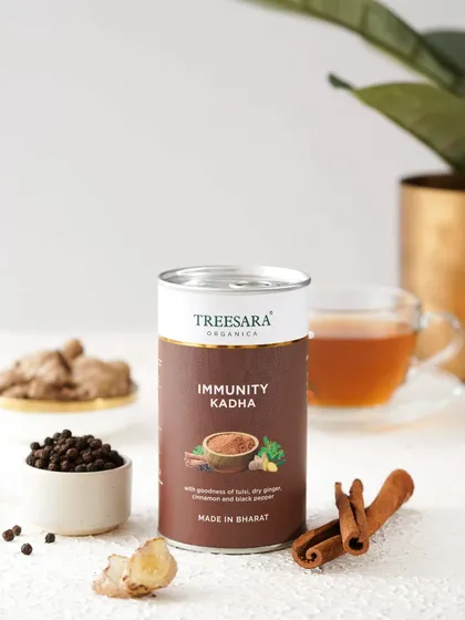 A shot of Immunity Kadha powder, with its key ingredients like cinnamon, pepper, and ginger displayed around it.