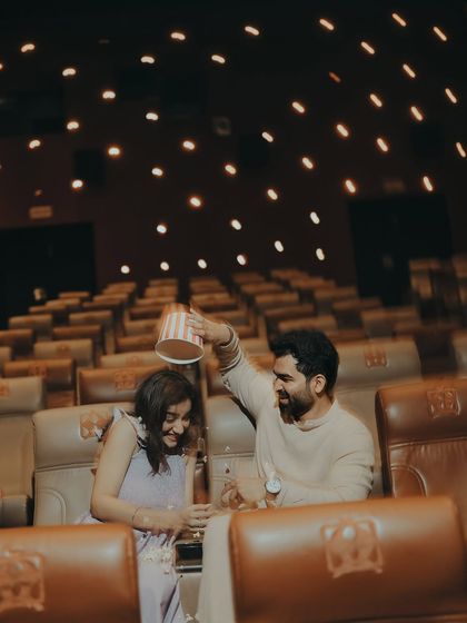 Laughter fills the empty theatre as the groom playfully tips a popcorn bucket. This candid shot captures the fun and spontaneity that makes each love story unique.