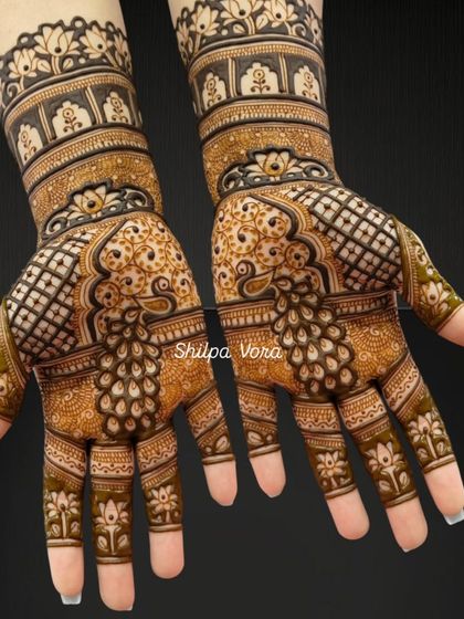 A beautiful design featuring peacock feathers and lotus motifs, extending from the wrist to the fingertips.