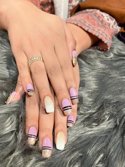 A unique mixed-finish set combining mauve polish, gold glitter, and black stripes for a creative and textured look.