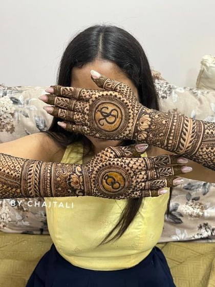 A popular pose to showcase engagement mehendi. This design features the couple's initials, 'S' and 'S', inside circular frames on the back of the hands.