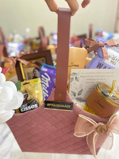 A chic and personalized thank you for the bride's tribe. This dusty pink quilted basket is filled with chocolates, a custom photo frame, and a personalized sipper, all brought together with a custom metal tag featuring the wedding hashtag.