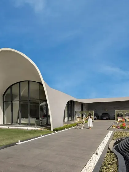 This is the hero item. We designed this modern fluidic outhouse in Punjab as a space for premier entertainment. Its signature architectural feature is a gracefully curved roof that recreates the form of a rising wave, creating a structure that is both a building and a sculpture.