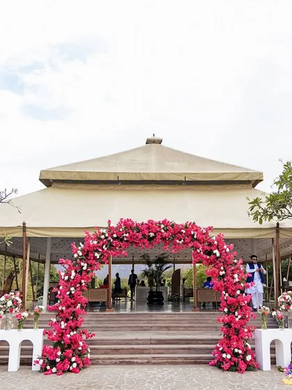 A beautiful floral arch of vibrant bougainvillea frames the entrance to this daytime event at Alila Fort Bishangarh, perfectly complementing the venue's natural beauty.