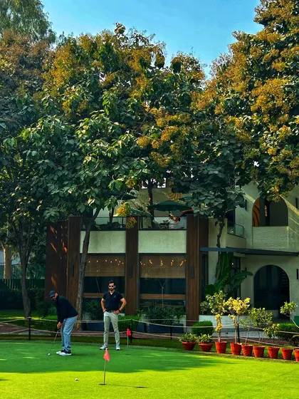 Two golfers on the putting green in front of our clubhouse, enjoying a sunny afternoon.
