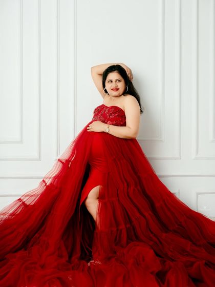 A confident and glamorous pose in a striking red gown. This shot celebrates the power and beauty of the mother-to-be with a bold, fashion-forward look.