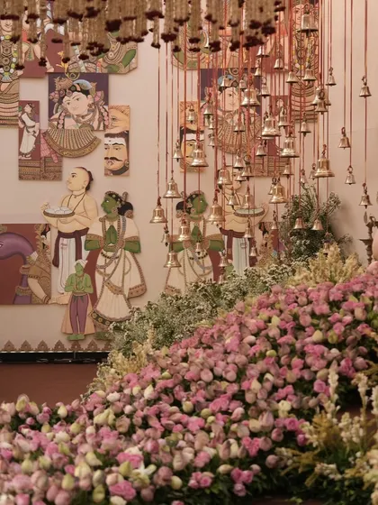 A beautiful combination of traditional Indian art panels, hanging temple bells, and a cascade of pink flowers, showing how I layer different cultural and natural elements.