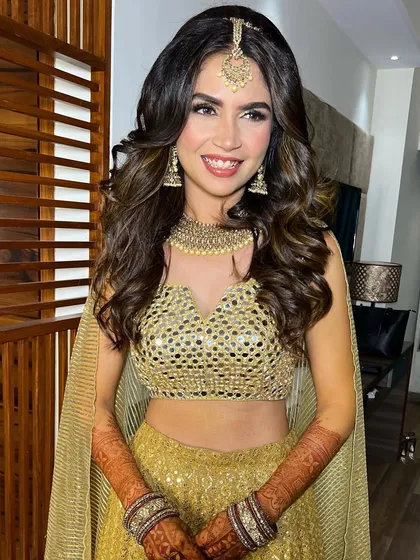 A full look of the Sangeet bride, smiling brightly. The mirror-work lehenga and glowing makeup are a perfect combination.