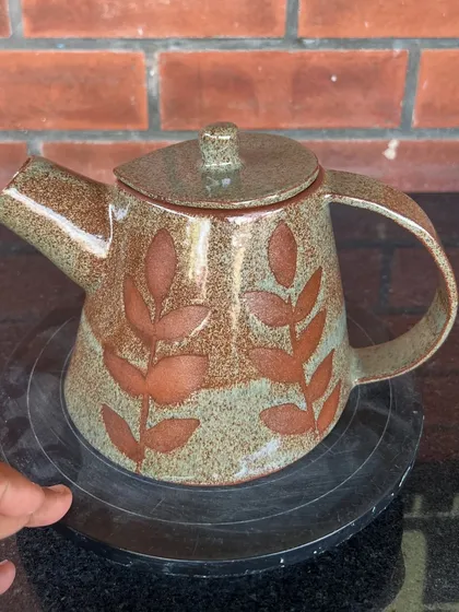 This teapot features a beautiful leaf pattern created with wax resist before glazing. It's a lovely example of combining form and surface decoration.