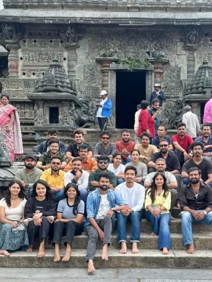 A group photo on the steps of a beautifully carved stone temple, showcasing the cultural richness of the regions we trek in.