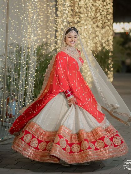 A full-length twirl shot of this gorgeous Gujarati bride in her unique red and white lehenga.