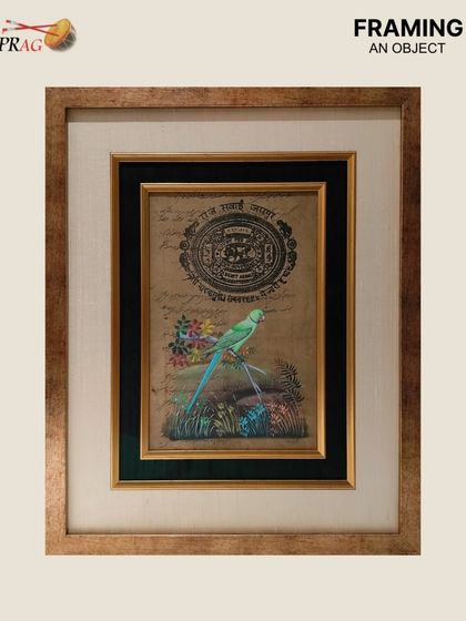 This antique document with a painted bird is a delicate piece of history. We designed a frame with multiple layers, including a silver box frame and a raw silk mount, to give it the visual weight and protection it deserves.