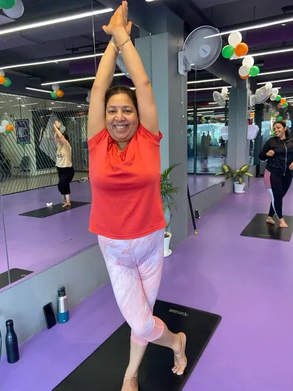 A participant joyfully holds a variation of the Eagle Pose, showing that yoga is adaptable for all body types and flexibility levels.