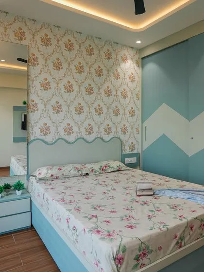 This charming bedroom combines a classic floral wallpaper with a playful chevron pattern on the sliding wardrobe. The scalloped headboard adds a touch of whimsy to the design.