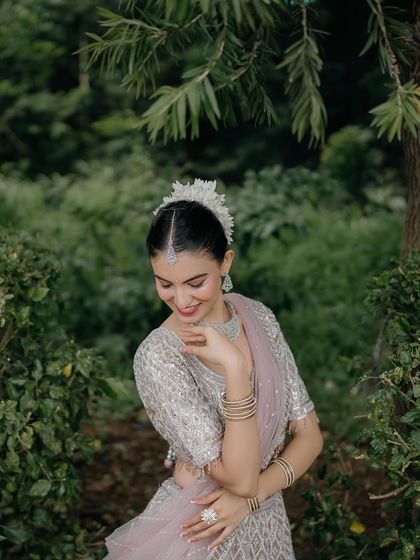 A sweet and shy smile. This close-up captures the bride's delicate features and the intricate details of her outfit and hair.