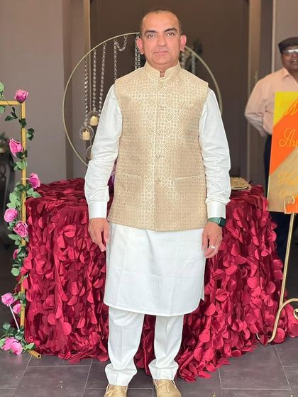 A happy client in London wearing a custom beige brocade waistcoat over a classic white kurta. This shows how my designs blend heritage and modernity, perfect for any setting.