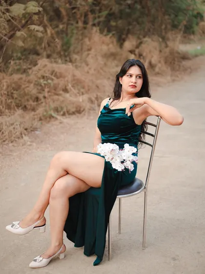 An elegant seated pose that showcases the entire silhouette of the green dress. It's a classic, graceful shot for any portfolio.