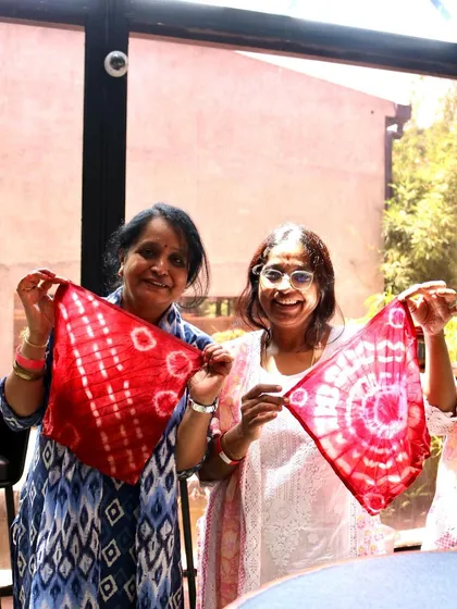 The joy of creating together! These two participants are thrilled with their finished napkins, each showcasing a different tie-dye pattern.