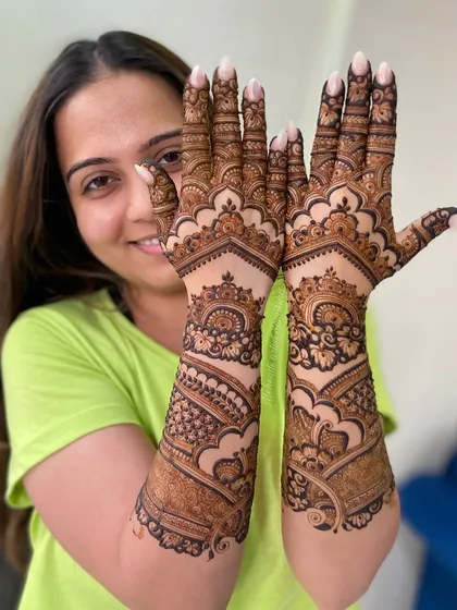 The prettiest client showing off her full-coverage engagement mehendi with a big smile.