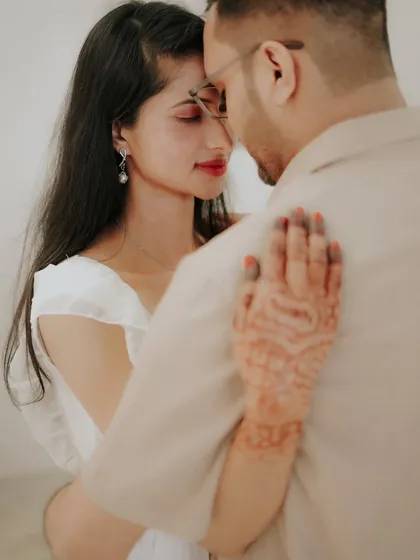 An intimate close-up from a romantic, themed shoot. The focus on the bride-to-be's henna-adorned hand adds a touch of tradition to this tender moment.