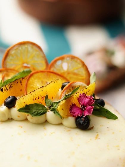 A close-up of a custom cake decorated with fresh oranges, blueberries, and edible flowers. We love using natural elements to create stunning and unique cake designs.