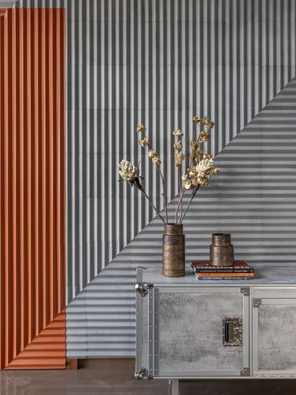 A detail shot showing the textural play of corrugated panels in grey and orange, used as a dynamic wall finish.