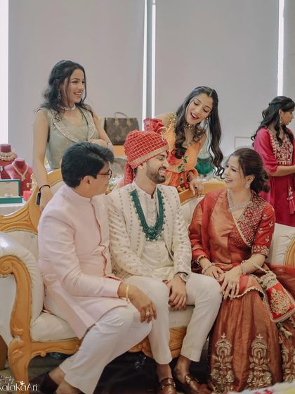 A candid family moment, with the groom sharing a laugh with his parents and sisters. These relaxed interactions make for the best memories.