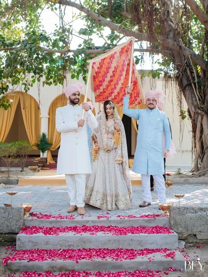 The bride's grand entrance, walking under a traditional phulkari dupatta held by her brothers.