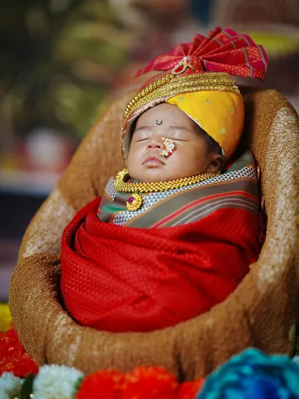 A peaceful portrait of the sleeping newborn, showcasing the rich colors and textures of the traditional Maharashtrian costume.