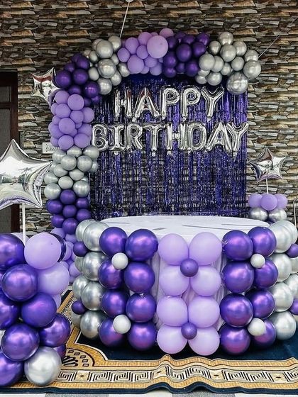 A full view of the purple and silver setup, including a balloon-decorated cake table.