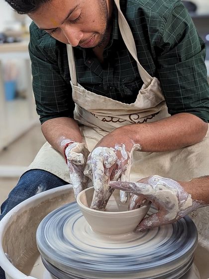 A moment of collaboration and learning at the wheel during one of our couples' pottery classes.