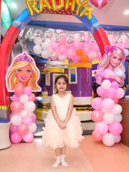 The birthday girl stands proudly at the entrance of her Barbie party. The custom arch with character cutouts makes her feel like the star of the show.