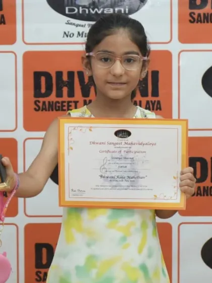 A young girl proudly holds her certificate and trophy.
