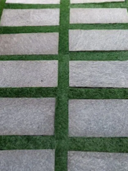 This is the same style of pathway, showing how the clean lines of the stone slabs contrast with the soft texture of the artificial grass. It's a practical and visually appealing hardscaping solution.