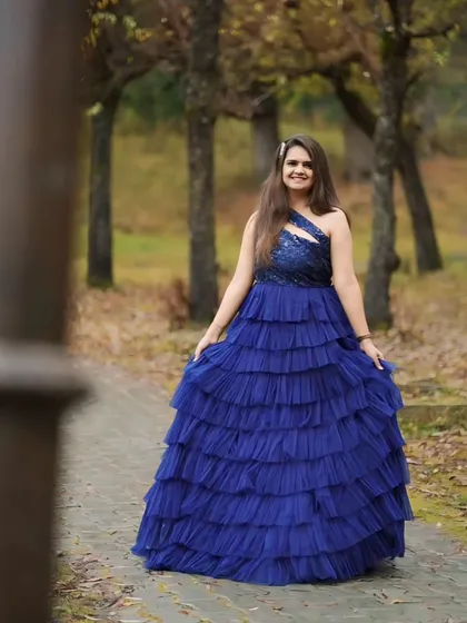 This navy blue gown features a heavily layered and ruffled skirt. It's a true statement piece that adds incredible texture and volume for a high-fashion pre-wedding look.