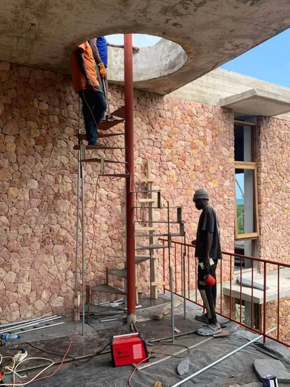 A spiral staircase is installed in one of the new buildings at Kizikula. The circular opening in the ceiling above will create a dramatic vertical connection between floors, letting in light from above.