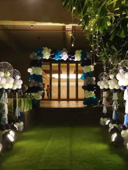 The beautifully lit entrance pathway for the starry night party. The path is lined with balloon bouquets topped with confetti and disco ball balloons, illuminated by spotlights.
