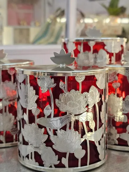 A close-up of the premium silver-plated jars with a beautiful lotus design against a red glass interior.