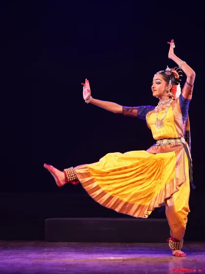A dancer captured mid-movement, her leg extended in a graceful arc, showcasing the beauty and dynamism of Bharatanatyam at the Sadhana festival.