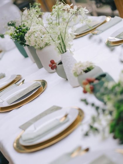 A long view of the organic tablescape, with gold-rimmed plates and simple, elegant floral arrangements.