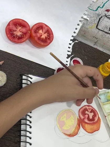 We believe in drawing from life. Here, a student practices observational drawing by painting a sliced tomato, learning to see and replicate colors, textures, and shapes accurately.