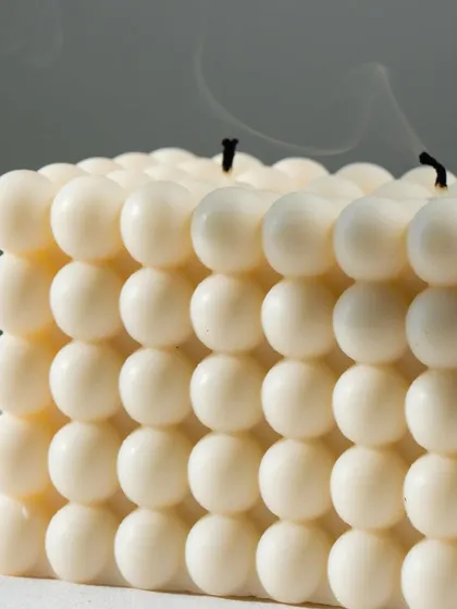 A large double-wick bubble candle after being extinguished, with gentle smoke trails rising. This shows the clean burn of our soy wax.
