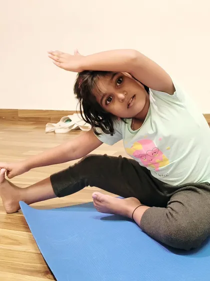 A young student finds her focus in a seated side stretch. These simple movements are wonderful for increasing spinal flexibility and creating space in the body.