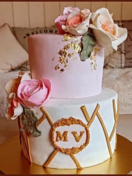 A stylish two-tier cake with a modern gold geometric pattern and delicate pink sugar flowers.