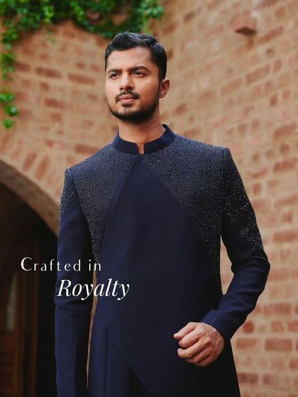 "Crafted in Royalty." This image for a designer lookbook captures the essence of regal elegance in a modern, asymmetrical navy blue sherwani.