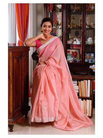 A seated version of the same look, showing the beautiful fall of the pink saree.
