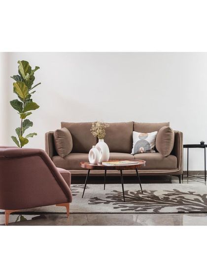 The living area in the 'House Under Tabebuia Trees' follows a minimal and neutral color palette. The focus is on clean forms, comfortable furnishings, and subtle details that create a serene and sophisticated living space.