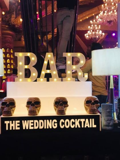 A detailed view of a themed bar with skull-shaped glasses and a marquee 'BAR' sign, perfect for a Halloween party or an edgy cocktail night.